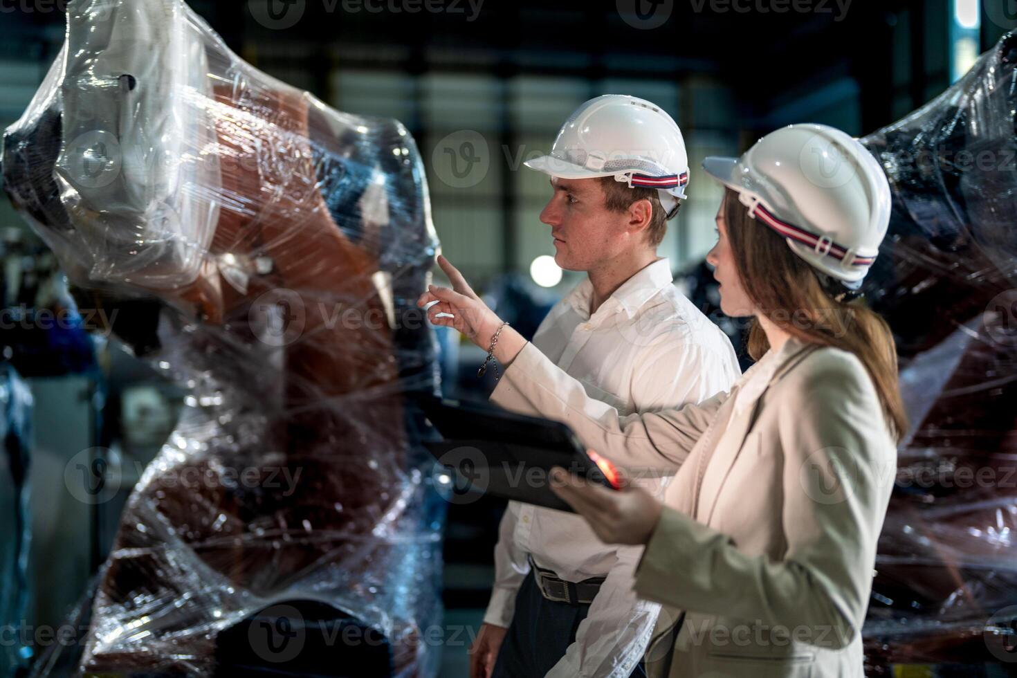 Sales manager and factory owner in suits negotiating selling robots used in the factory. Business engineers meeting and checking new machine robot. Workers walking at warehouse welding machine. photo