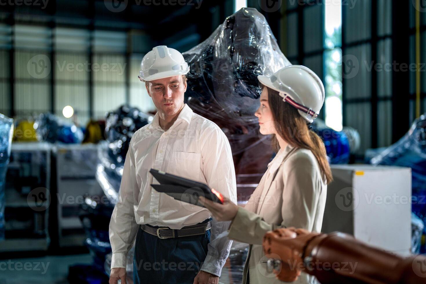 Business engineers meeting and checking new machine robot. Workers walking at warehouse industry welding machine. business negotiation concepts and technology. women Using smart Tablet to present man. photo