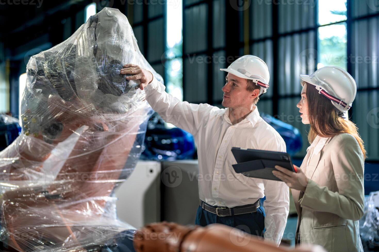 Sales manager and factory owner in suits negotiating selling robots used in the factory. Business engineers meeting and checking new machine robot. Workers walking at warehouse welding machine. photo