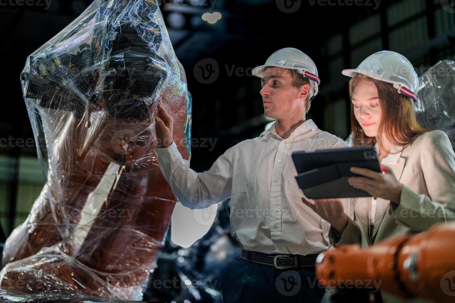 Business engineers meeting and checking new machine robot. Workers walking at warehouse industry welding machine. business negotiation concepts and technology. women Using smart Tablet to present man. photo