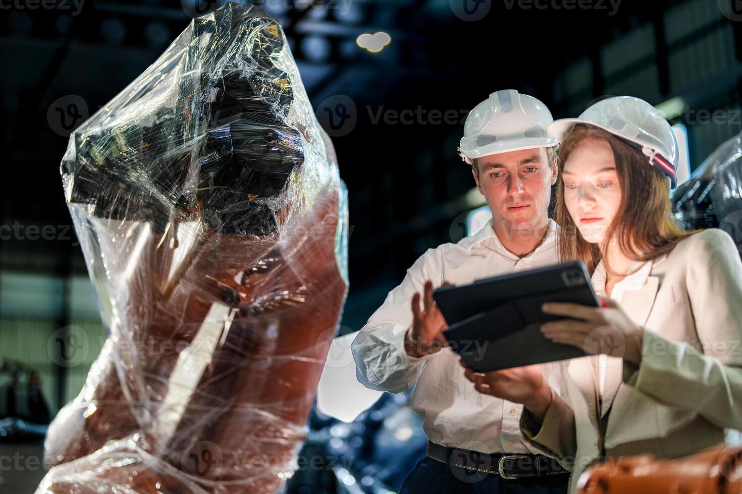 Business engineers meeting and checking new machine robot. Workers walking at warehouse industry welding machine. business negotiation concepts and technology. women Using smart Tablet to present man. photo