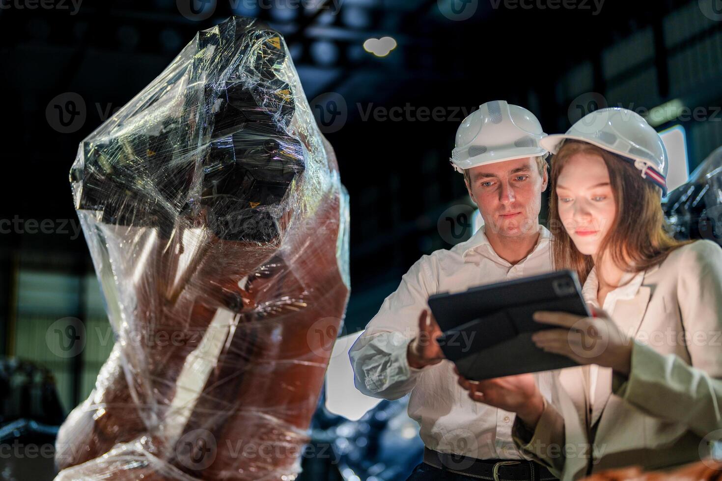 Sales manager and factory owner in suits negotiating selling robots used in the factory. Business engineers meeting and checking new machine robot. Workers walking at warehouse welding machine. photo