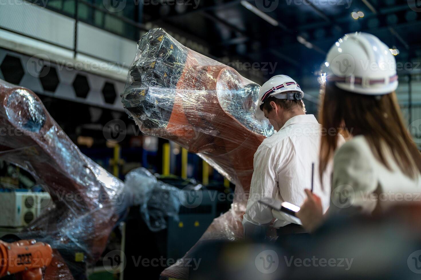 Business engineers meeting and checking new machine robot. Workers walking at warehouse industry welding machine. business negotiation concepts and technology. women Using smart Tablet to present man. photo