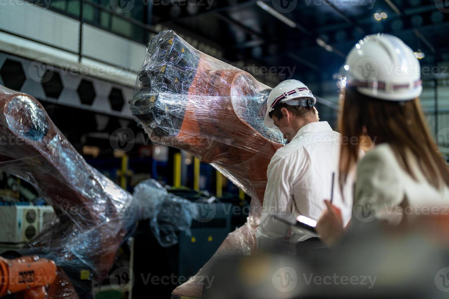 Business engineers meeting and checking new machine robot. Workers walking at warehouse industry welding machine. business negotiation concepts and technology. women Using smart Tablet to present man. photo