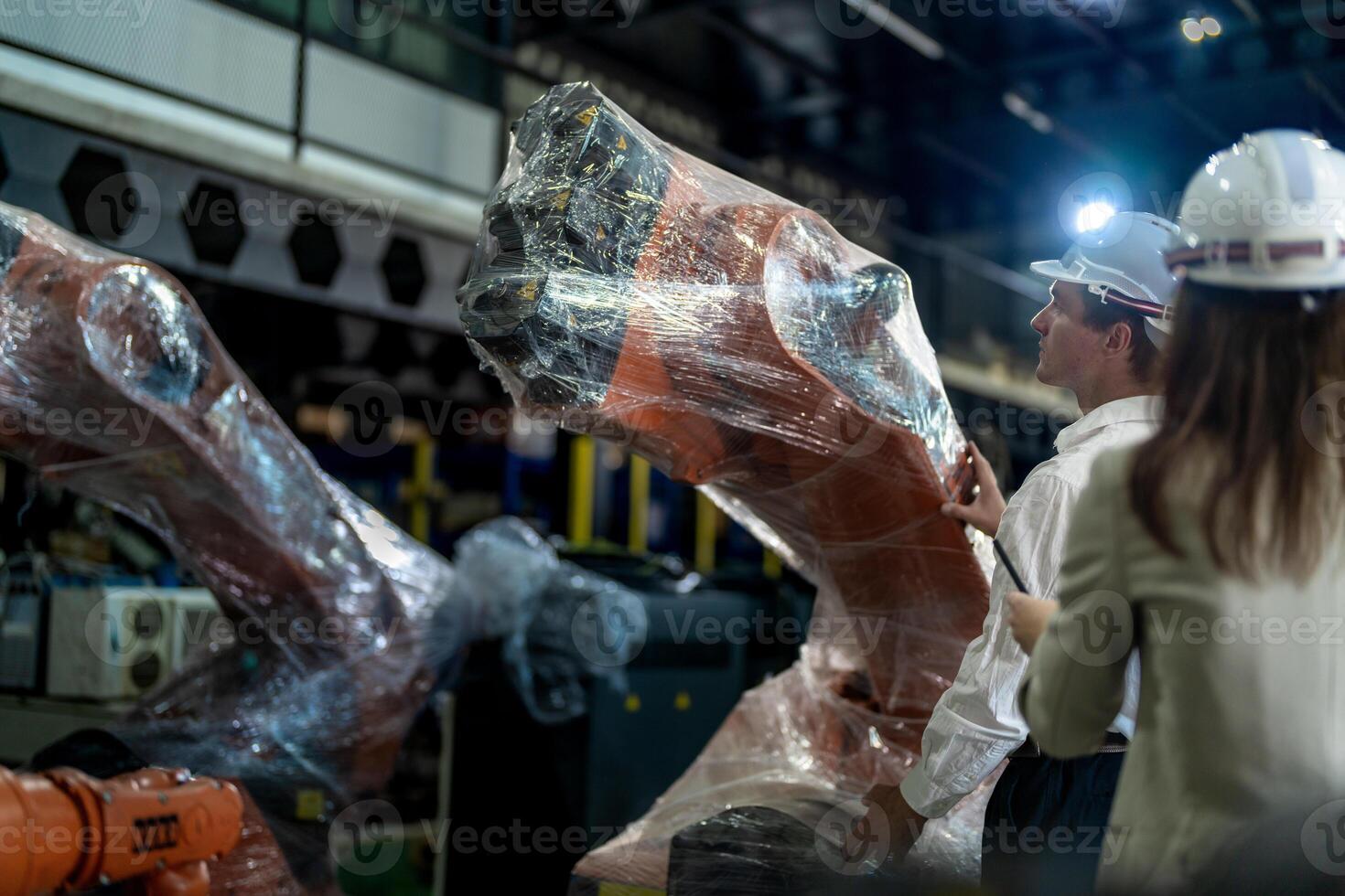 Business engineers meeting and checking new machine robot. Workers walking at warehouse industry welding machine. business negotiation concepts and technology. women Using smart Tablet to present man. photo