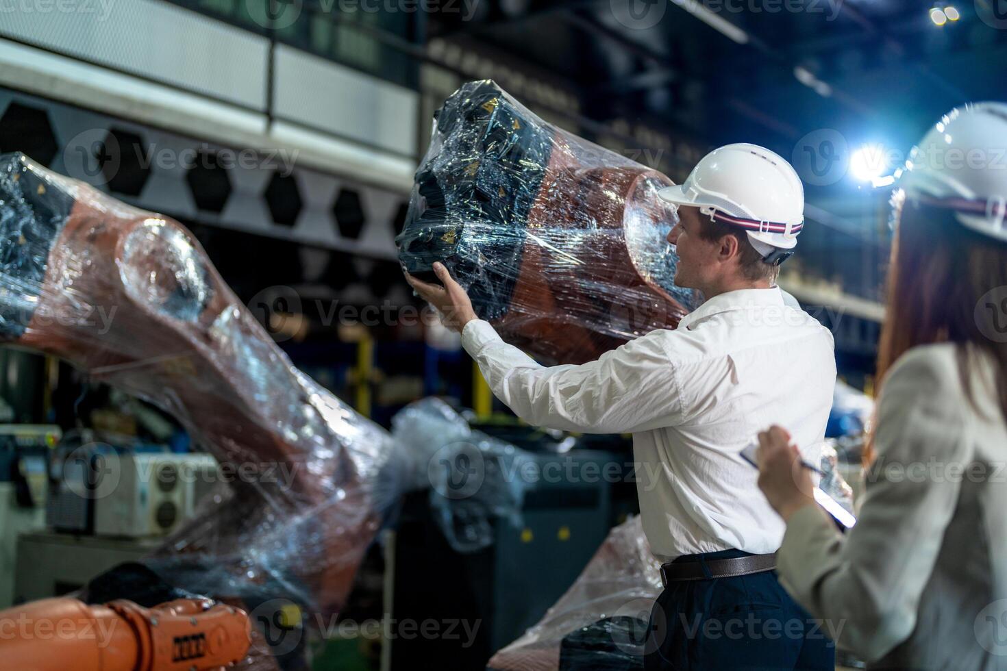 Business engineers meeting and checking new machine robot. Workers walking at warehouse industry welding machine. business negotiation concepts and technology. women Using smart Tablet to present man. photo