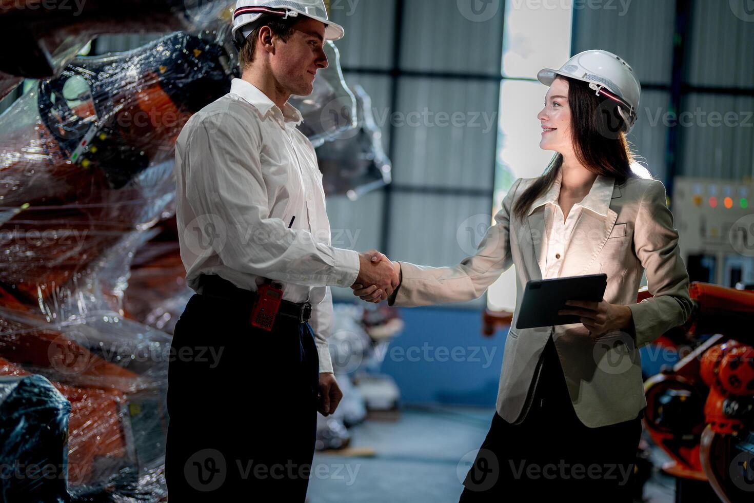Business engineers meeting and checking new machine robot. Workers walking at warehouse industry welding machine. business negotiation concepts and technology. women Using smart Tablet to present man. photo