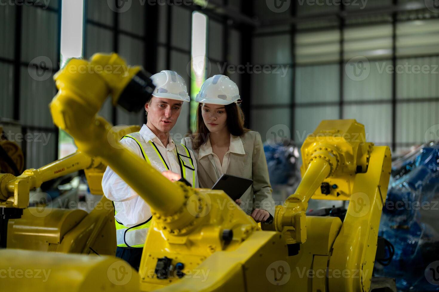 Factory engineers inspecting on machine with smart tablet. Worker works at machine robot arm. The welding machine with a remote system in an industrial factory. Artificial intelligence concept. photo