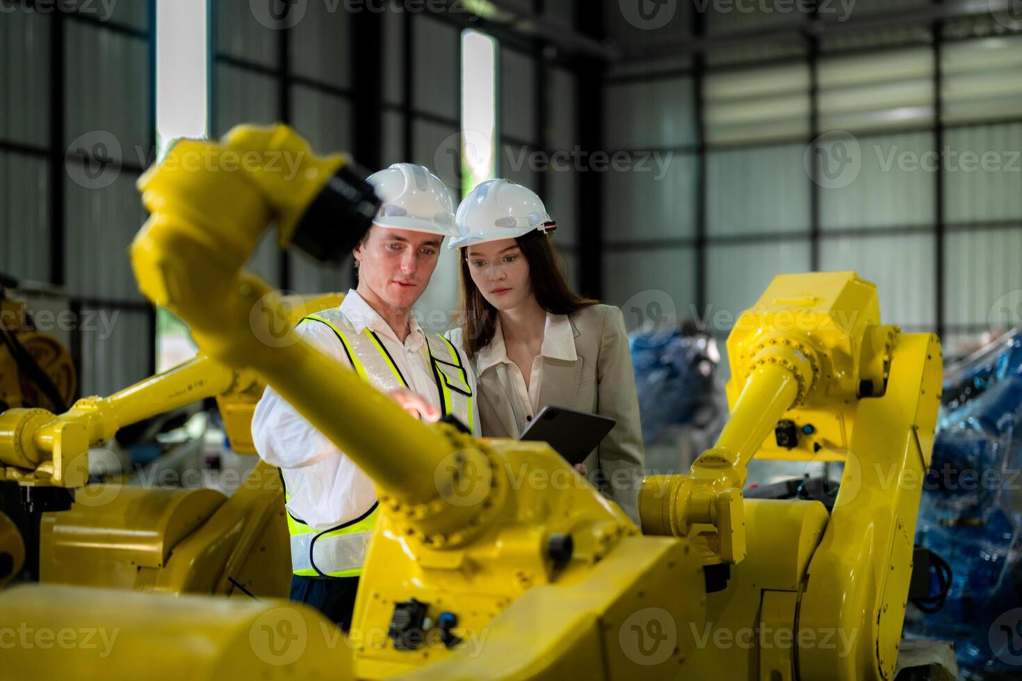Factory engineers inspecting on machine with smart tablet. Worker works at machine robot arm. The welding machine with a remote system in an industrial factory. Artificial intelligence concept. photo