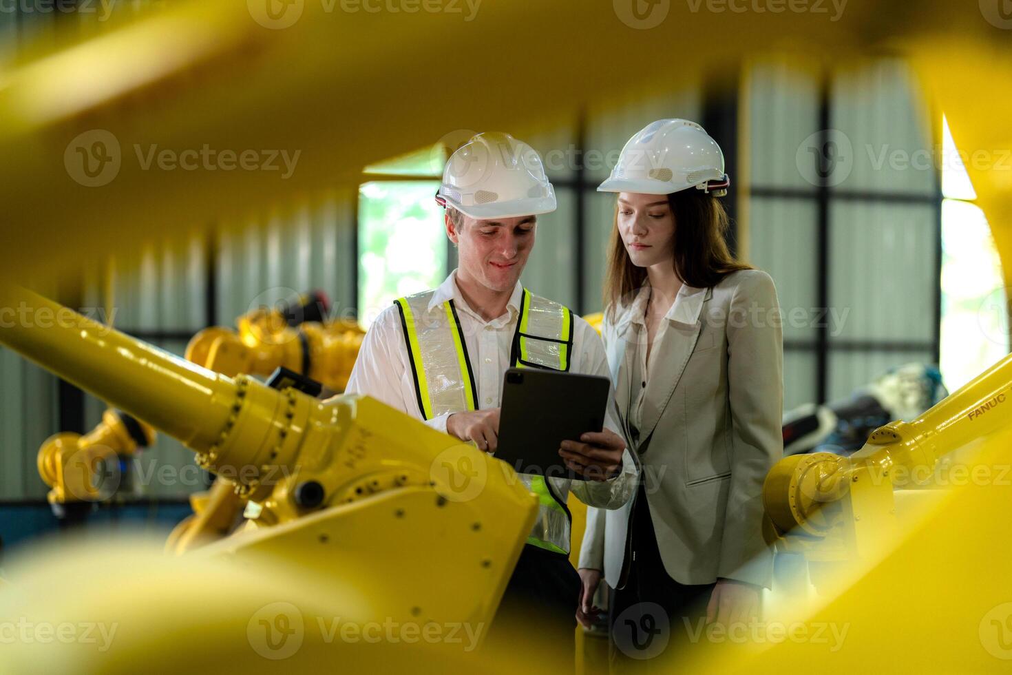 Factory engineers inspecting on machine with smart tablet. Worker works at machine robot arm. The welding machine with a remote system in an industrial factory. Artificial intelligence concept. photo