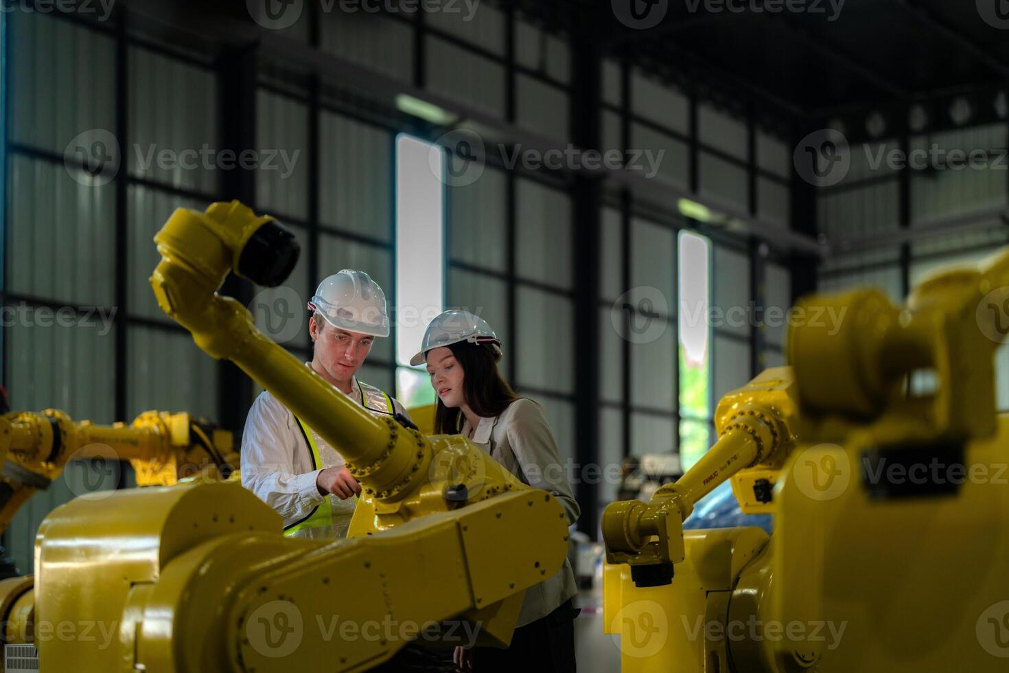 Factory engineers inspecting on machine with smart tablet. Worker works at heavy machine robot arm. The welding machine with a remote system in an industrial factory. Artificial intelligence concept. photo