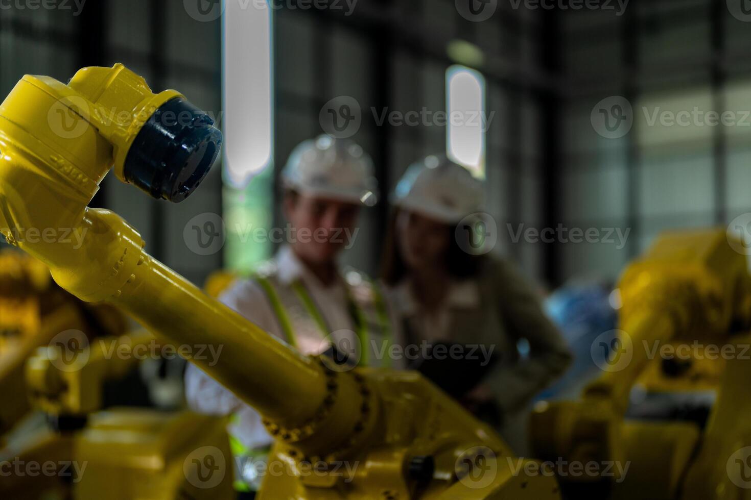 Factory engineers inspecting on machine with smart tablet. Worker works at heavy machine robot arm. The welding machine with a remote system in an industrial factory. Artificial intelligence concept. photo