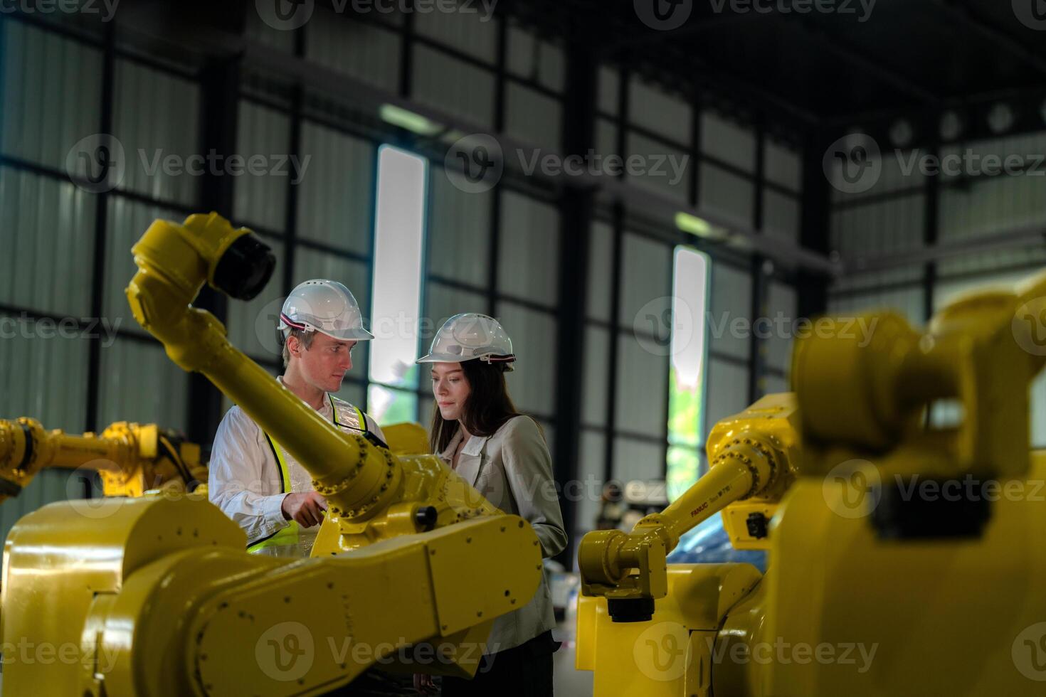 Factory engineers inspecting on machine with smart tablet. Worker works at heavy machine robot arm. The welding machine with a remote system in an industrial factory. Artificial intelligence concept. photo
