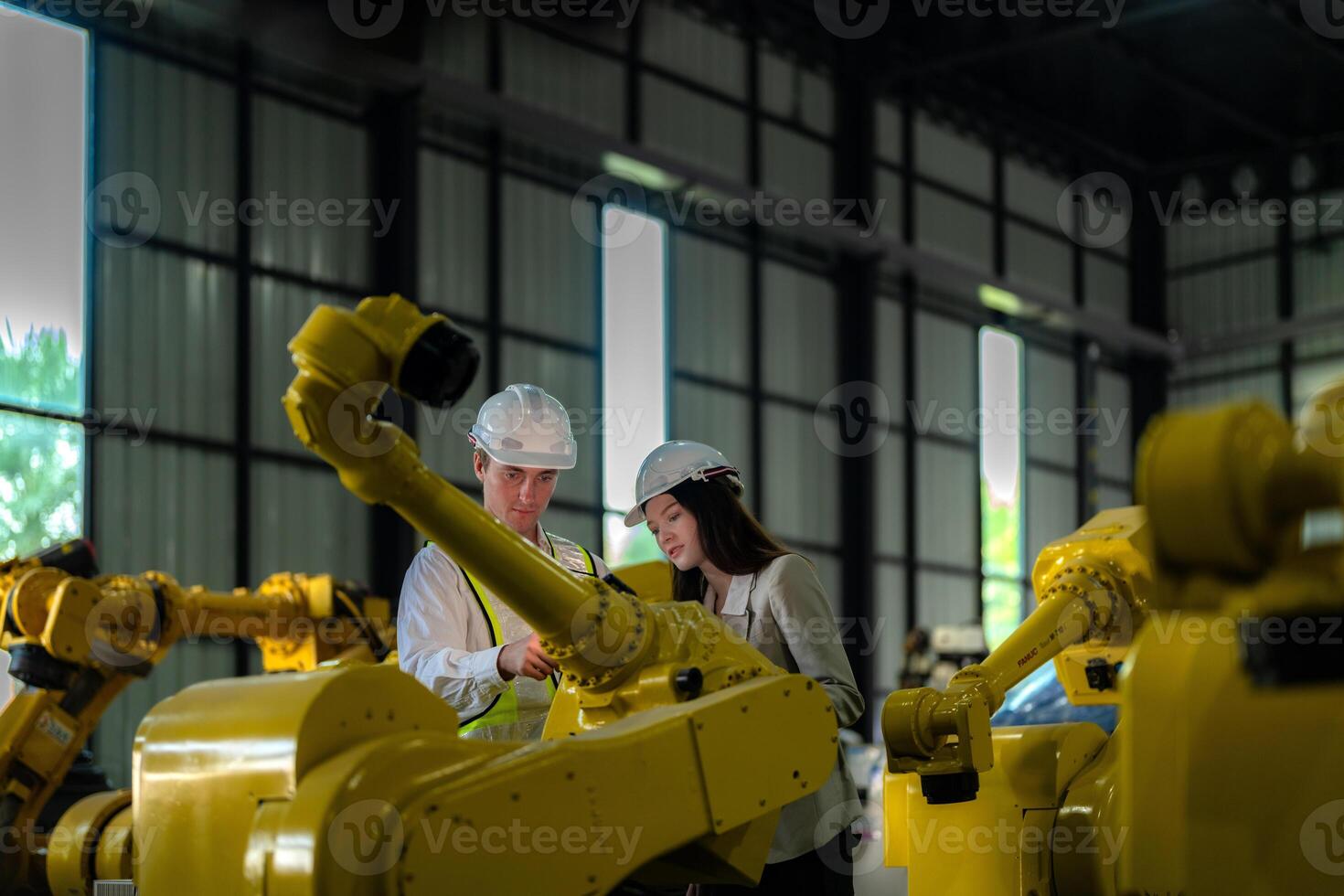 Factory engineers inspecting on machine with smart tablet. Worker works at heavy machine robot arm. The welding machine with a remote system in an industrial factory. Artificial intelligence concept. photo