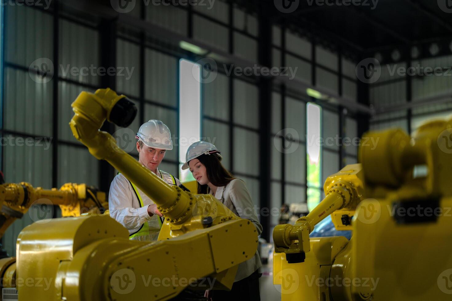 Factory engineers inspecting on machine with smart tablet. Worker works at heavy machine robot arm. The welding machine with a remote system in an industrial factory. Artificial intelligence concept. photo