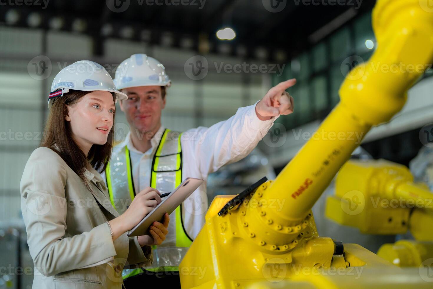 Factory engineers inspecting on machine with smart tablet. Worker works at heavy machine robot arm. The welding machine with a remote system in an industrial factory. Artificial intelligence concept. photo