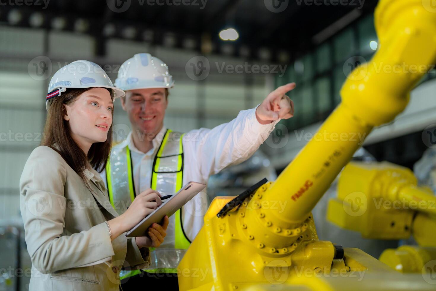 Factory engineers inspecting on machine with smart tablet. Worker works at heavy machine robot arm. The welding machine with a remote system in an industrial factory. Artificial intelligence concept. photo