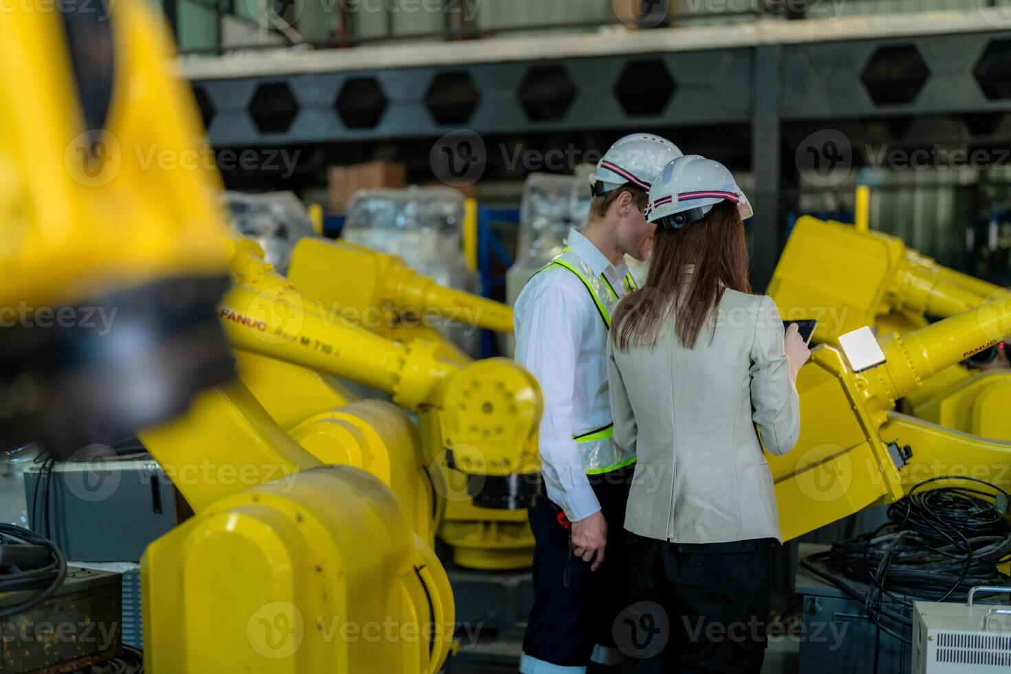 Factory engineers inspecting on machine with smart tablet. Worker works at heavy machine robot arm. The welding machine with a remote system in an industrial factory. Artificial intelligence concept. photo