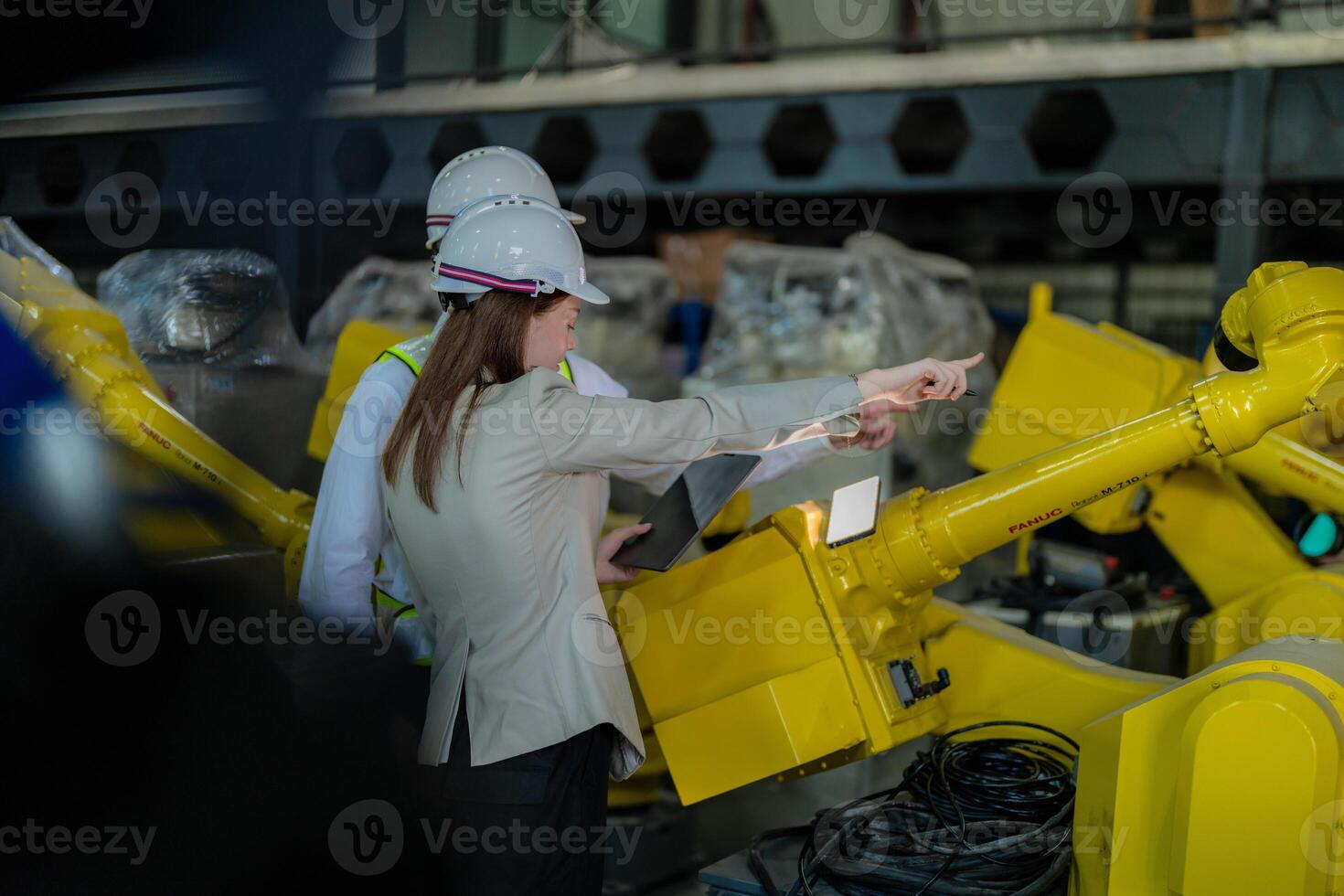 Factory engineers inspecting on machine with smart tablet. Worker works at heavy machine robot arm. The welding machine with a remote system in an industrial factory. Artificial intelligence concept. photo