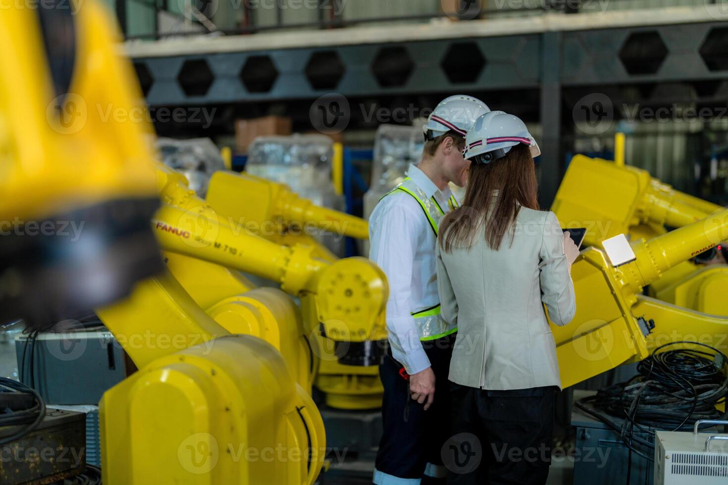 Factory engineers inspecting on machine with smart tablet. Worker works at heavy machine robot arm. The welding machine with a remote system in an industrial factory. Artificial intelligence concept. photo