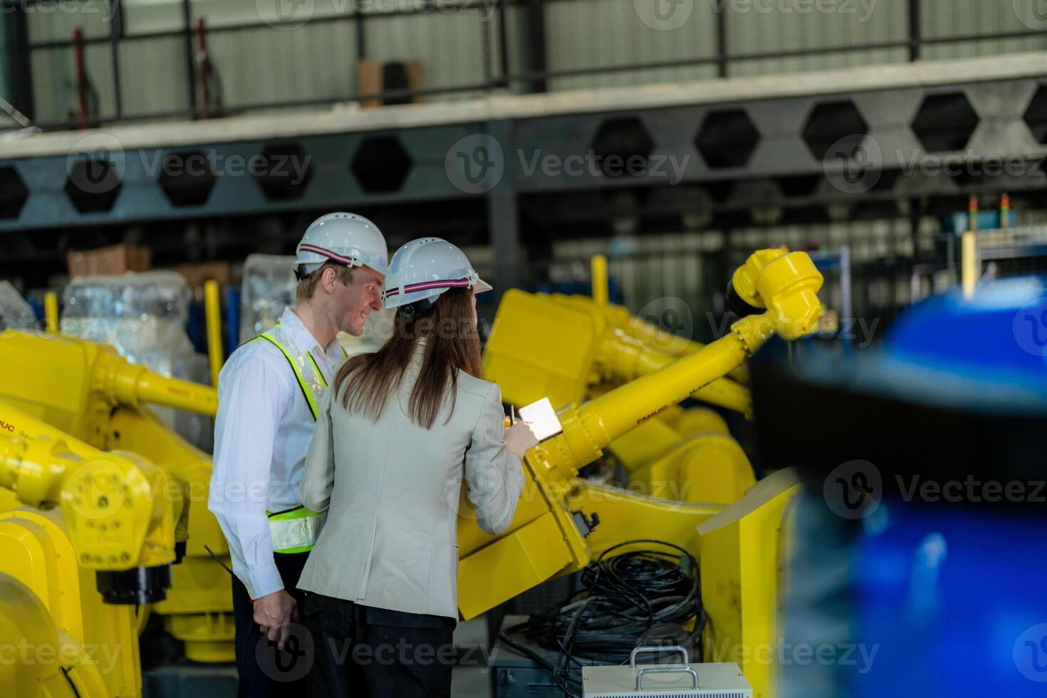 Factory engineers inspecting on machine with smart tablet. Worker works at heavy machine robot arm. The welding machine with a remote system in an industrial factory. Artificial intelligence concept. photo