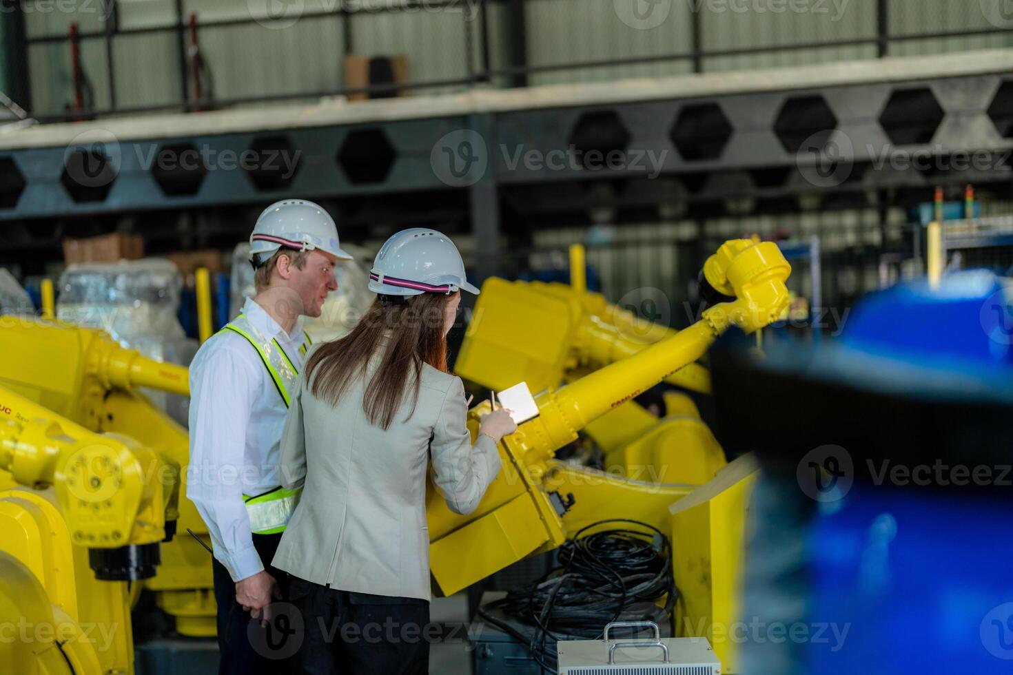 Factory engineers inspecting on machine with smart tablet. Worker works at heavy machine robot arm. The welding machine with a remote system in an industrial factory. Artificial intelligence concept. photo