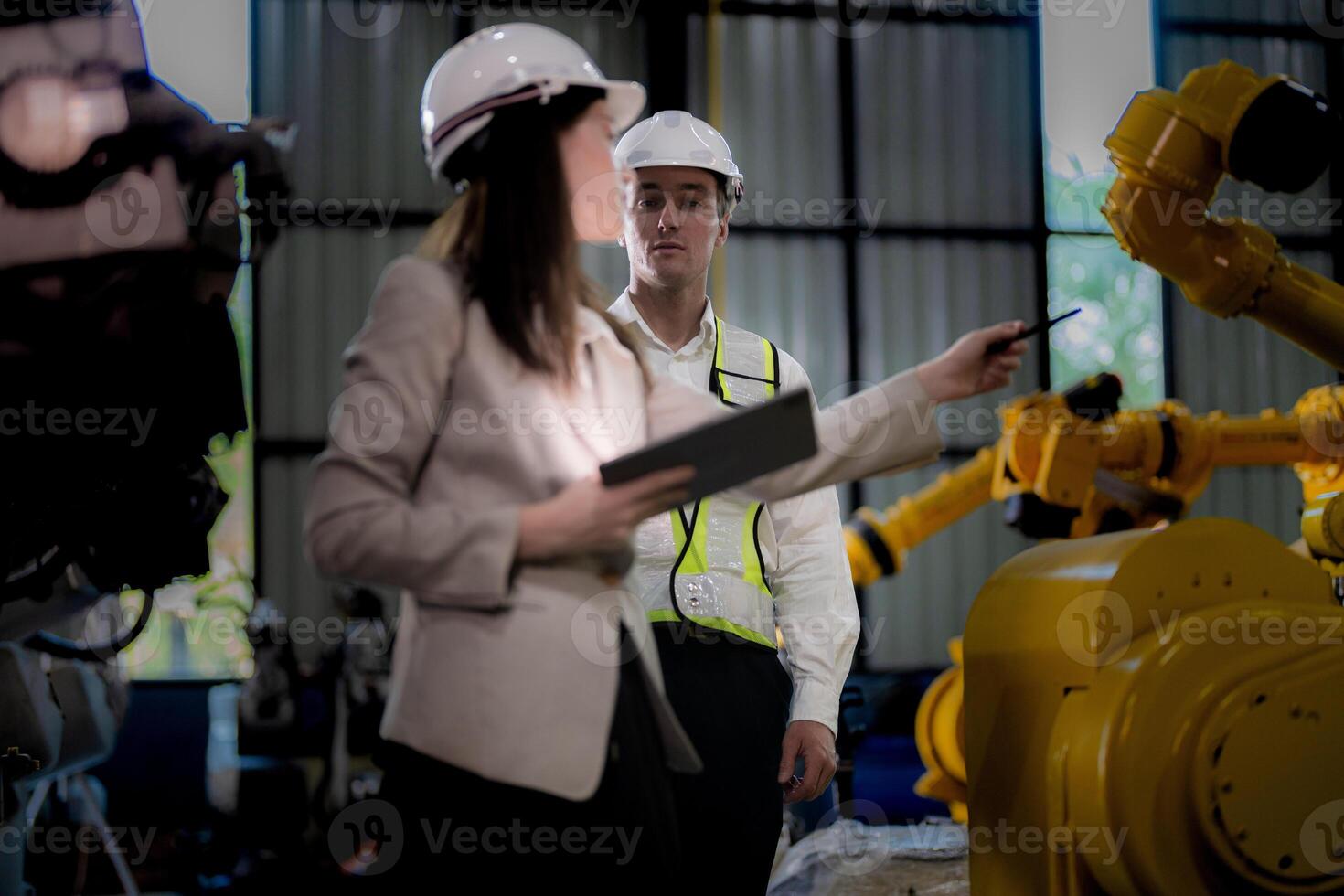 Business woman and man meeting and checking new machine robot. Engineer walking at warehouse industry machine. business negotiation concepts and technology. woman is Using smart Tablet to present man. photo