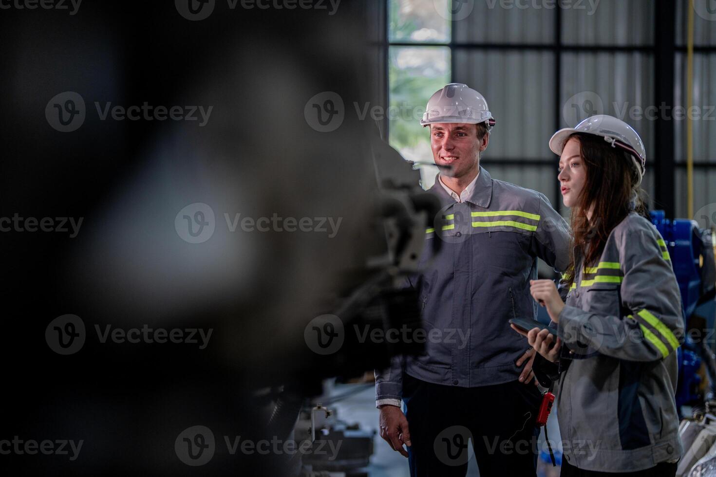 Factory engineer woman inspecting on machine with smart tablet. Worker works at machine robot arm. The welding machine with a remote system in an industrial factory. Artificial intelligence concept. photo