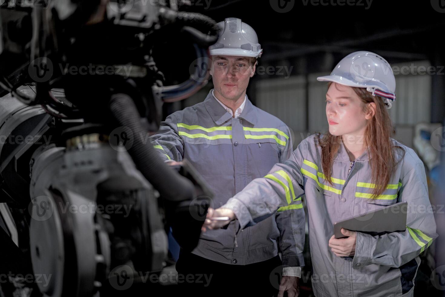 Business engineers meet and check control heavy machine robot arm. Diverse Team of Industrial Robotics Engineers Gathered Around machine. Professional Machinery Operator Use Industrial Digital Tablet. photo