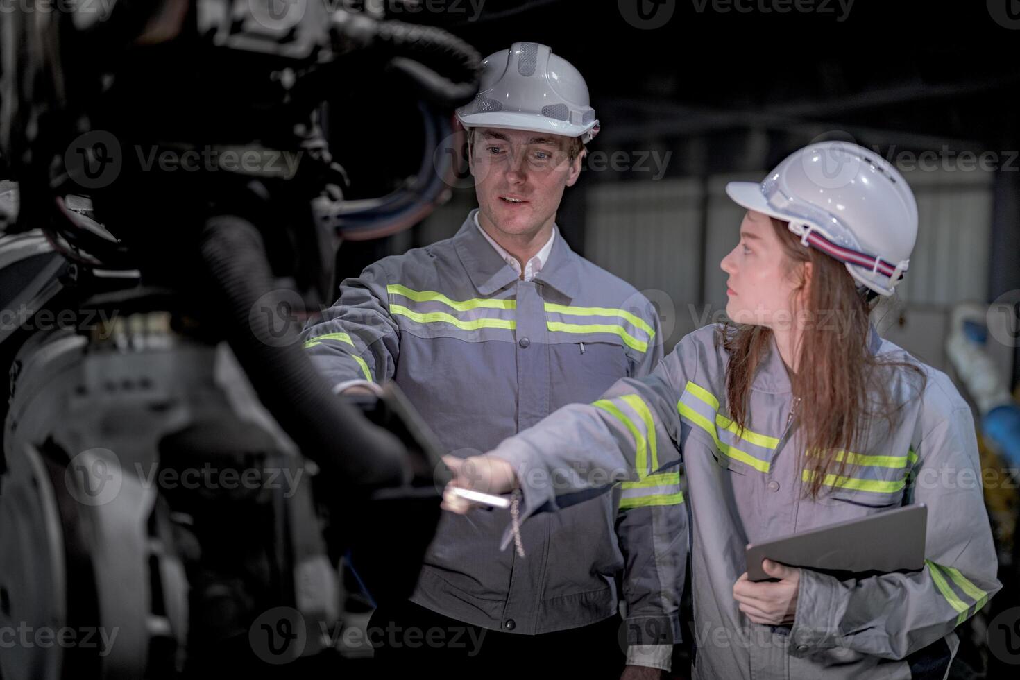 Business engineers meet and check control heavy machine robot arm. Diverse Team of Industrial Robotics Engineers Gathered Around machine. Professional Machinery Operator Use Industrial Digital Tablet. photo