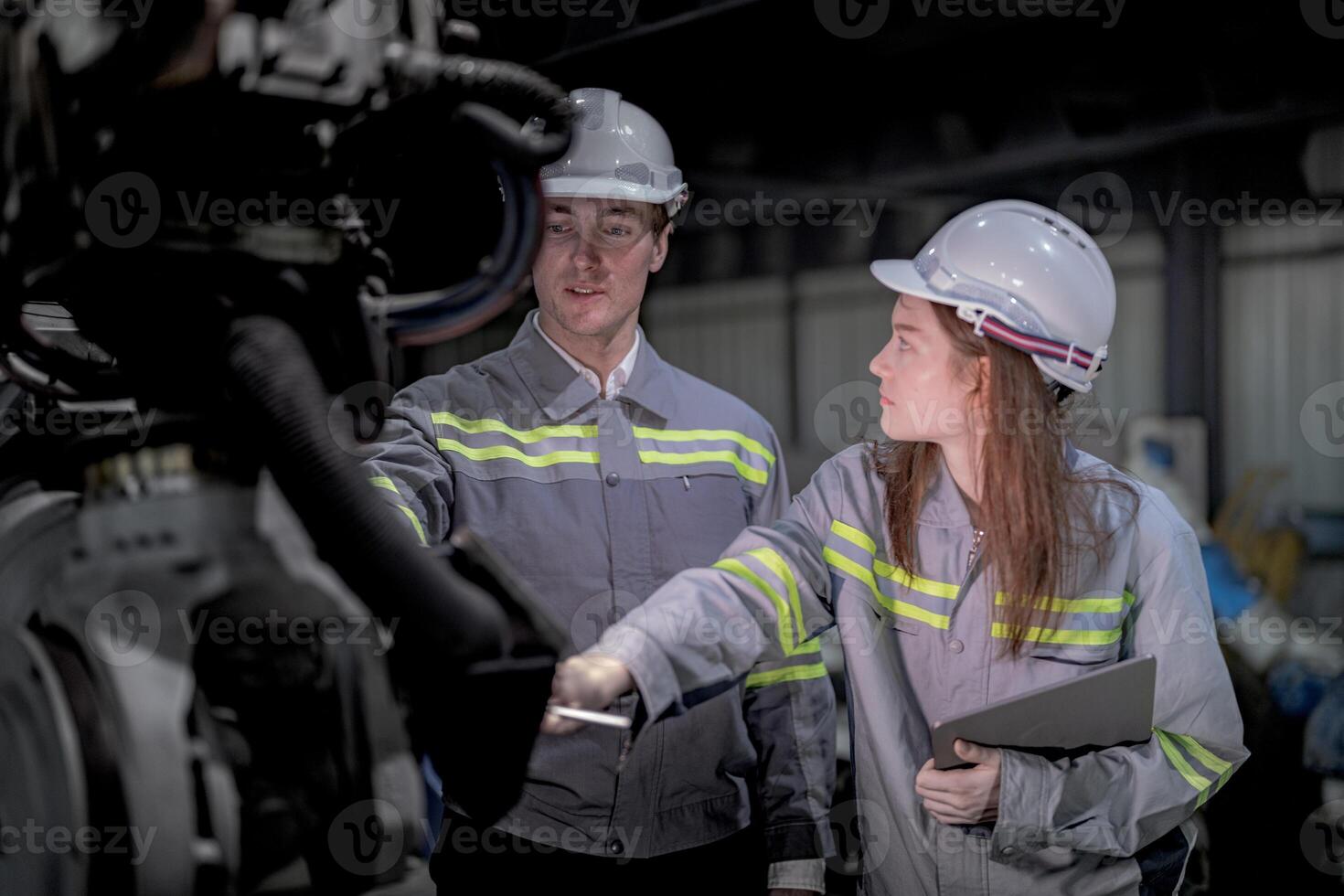 Business engineers meet and check control heavy machine robot arm. Diverse Team of Industrial Robotics Engineers Gathered Around machine. Professional Machinery Operator Use Industrial Digital Tablet. photo