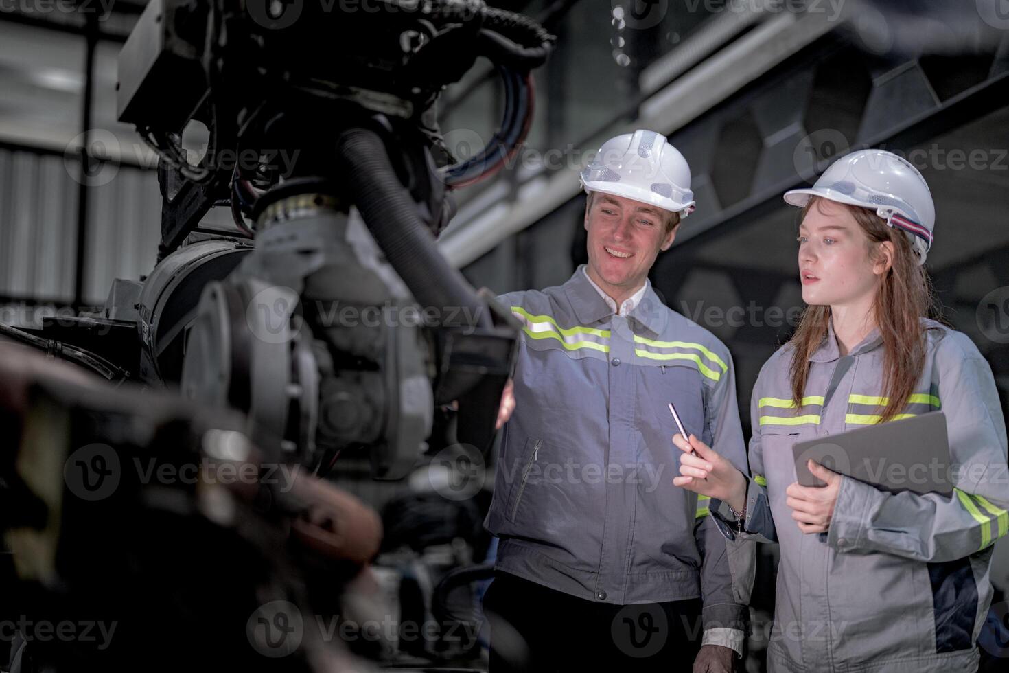 Business engineers meet and check control heavy machine robot arm. Diverse Team of Industrial Robotics Engineers Gathered Around machine. Professional Machinery Operator Use Industrial Digital Tablet. photo