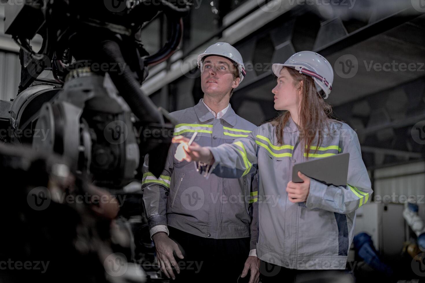 Sales manager and factory owner in suits negotiating selling robots used in the factory. Business engineers meeting and checking new machine robot. Workers walking at warehouse welding machine. photo