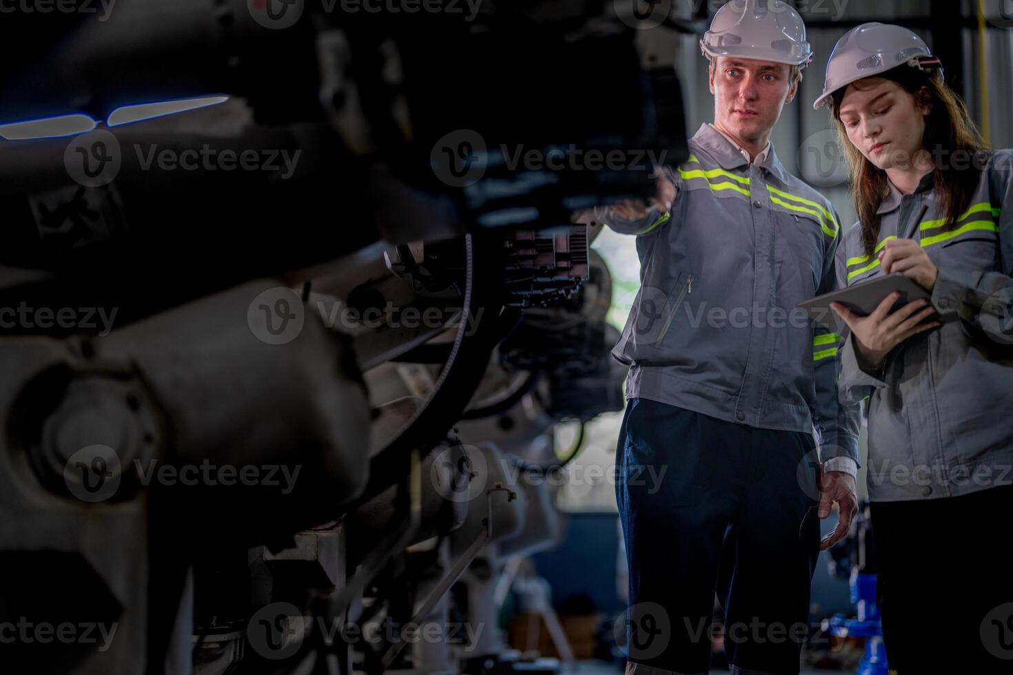 Factory engineer woman inspecting on machine with smart tablet. Worker works at machine robot arm. The welding machine with a remote system in an industrial factory. Artificial intelligence concept. photo