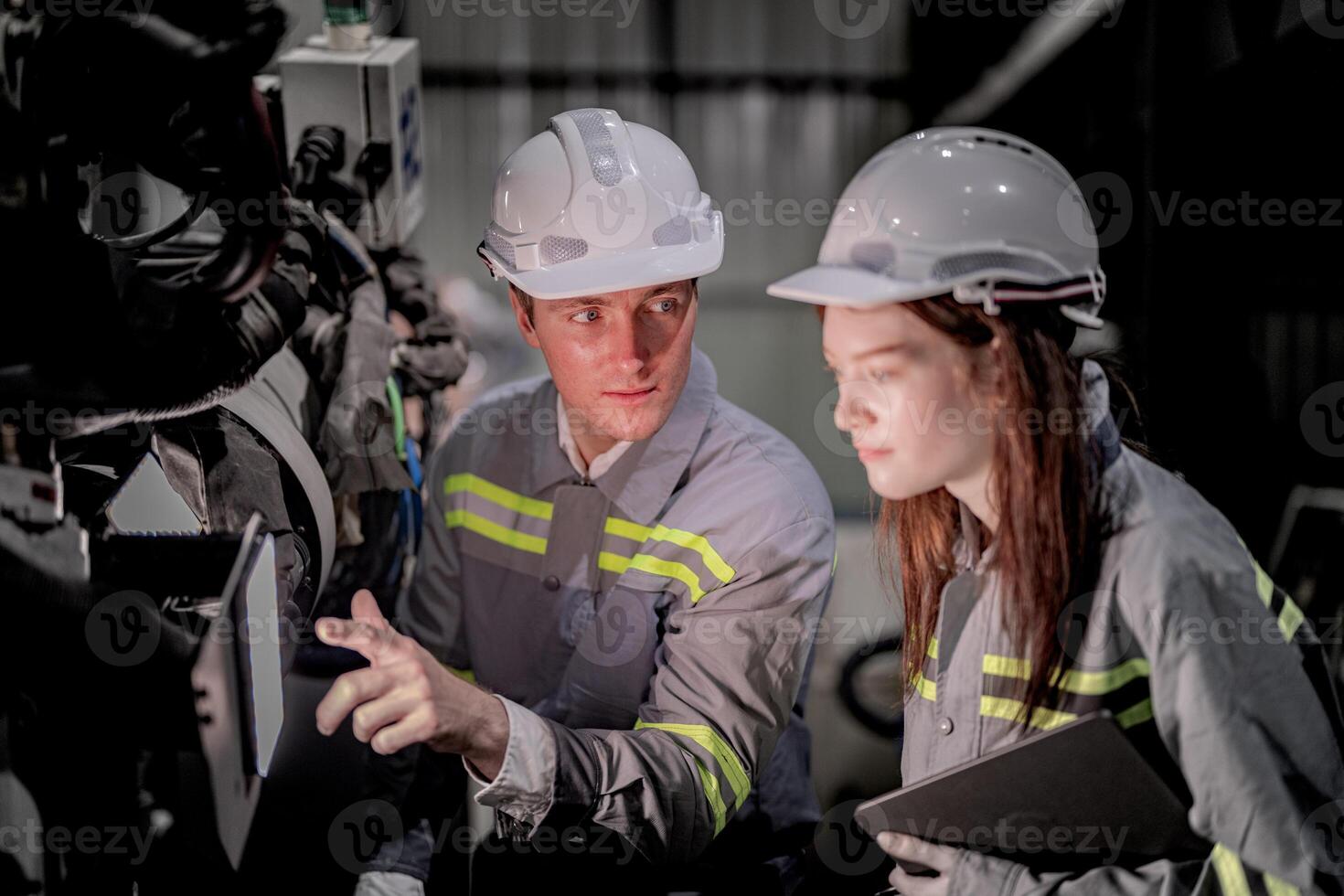 negocio ingenieros reunirse y cheque controlar pesado máquina robot brazo. diverso equipo de industrial robótica ingenieros reunido alrededor máquina. profesional maquinaria operador utilizar industrial digital tableta. foto