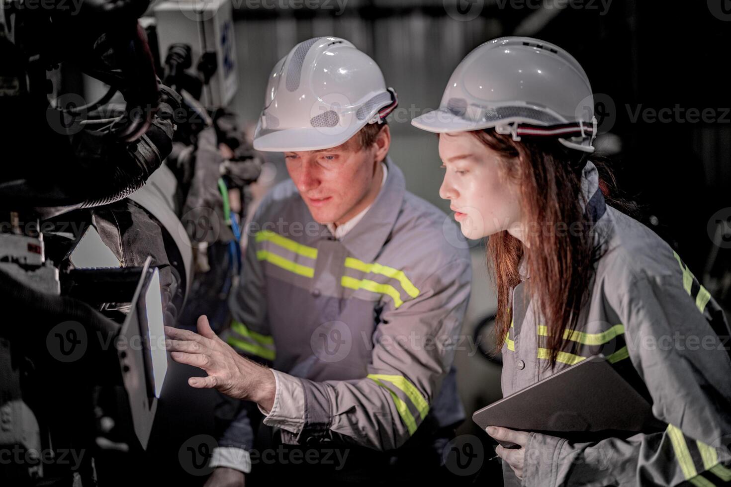 Business engineers meet and check control heavy machine robot arm. Diverse Team of Industrial Robotics Engineers Gathered Around machine. Professional Machinery Operator Use Industrial Digital Tablet. photo