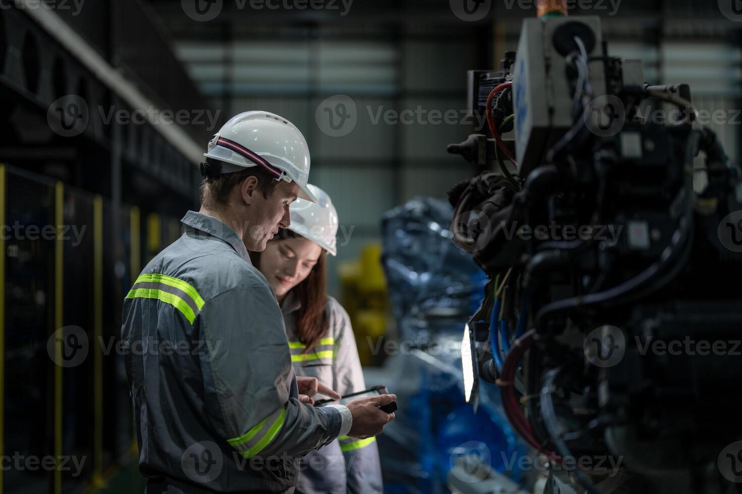 Factory engineer woman inspecting on machine with smart tablet. Worker works at machine robot arm. The welding machine with a remote system in an industrial factory. Artificial intelligence concept. photo