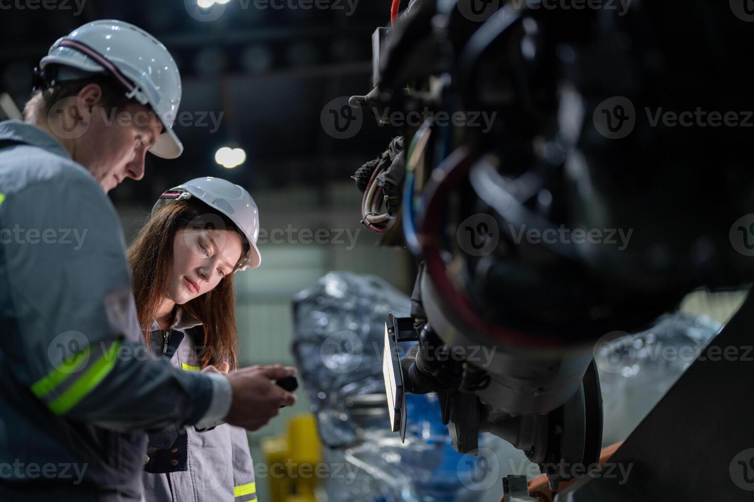 Factory engineer woman inspecting on machine with smart tablet. Worker works at machine robot arm. The welding machine with a remote system in an industrial factory. Artificial intelligence concept. photo