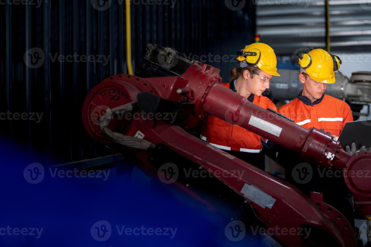 group of male engineer workers maintenance automatic robotic arm machine in a dark room factory. worker checking and repairing automatic robot hand machine. Worker wearing safety glasses and helmet. photo