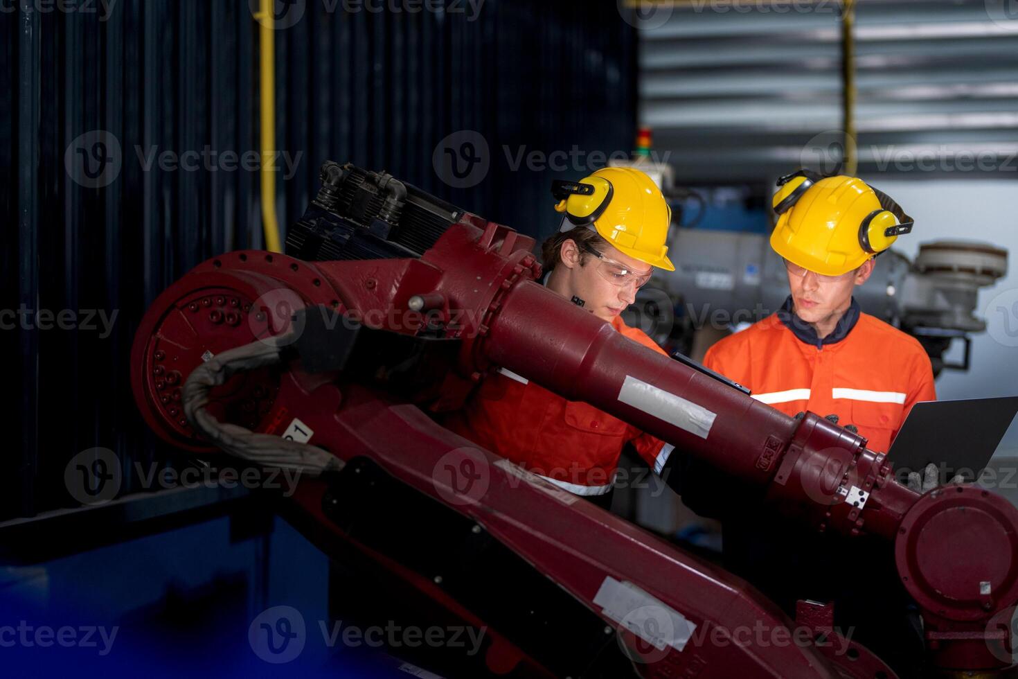 group of male engineer workers maintenance automatic robotic arm machine in a dark room factory. worker checking and repairing automatic robot hand machine. Worker wearing safety glasses and helmet. photo