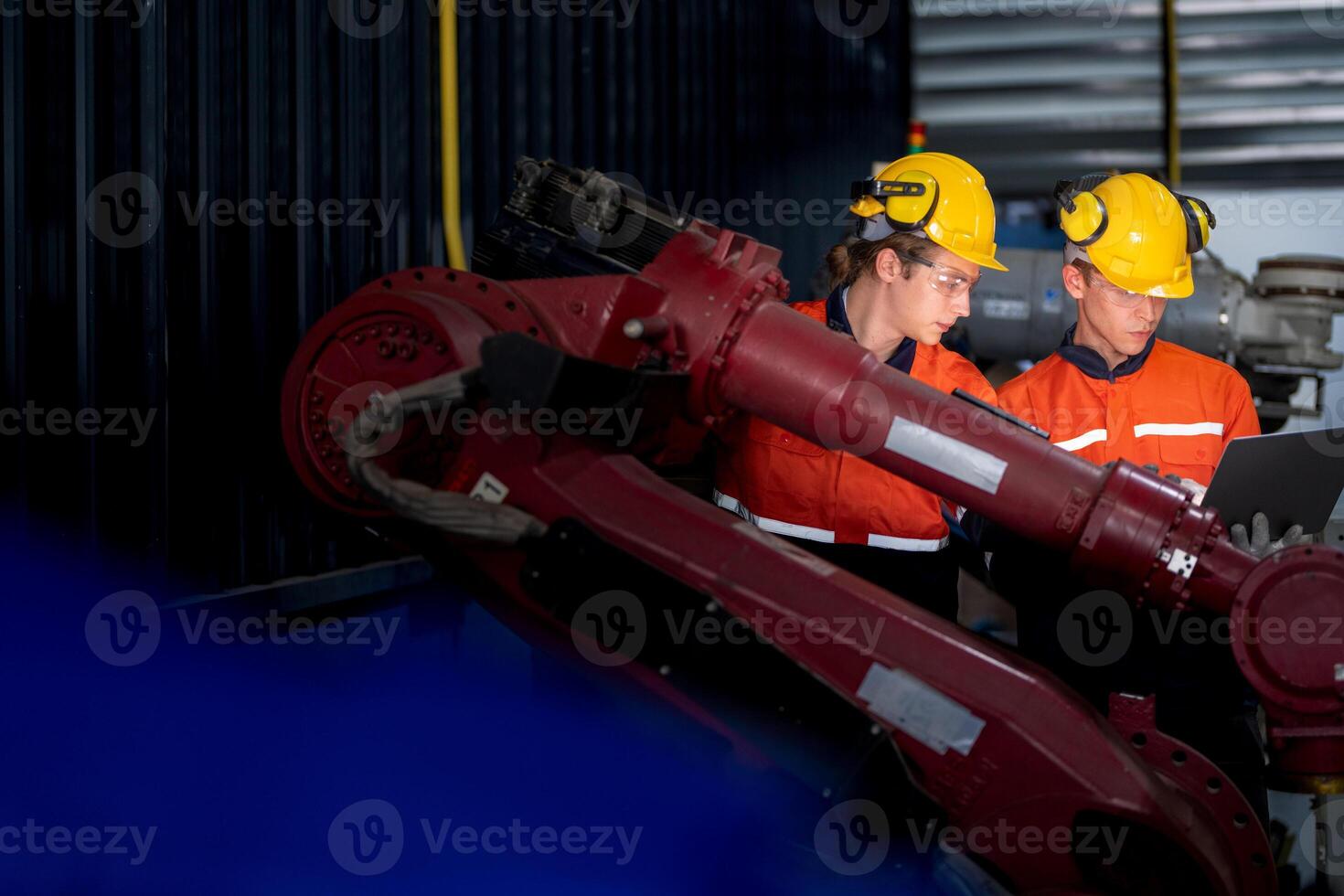 group of male engineer workers maintenance automatic robotic arm machine in a dark room factory. worker checking and repairing automatic robot hand machine. Worker wearing safety glasses and helmet. photo