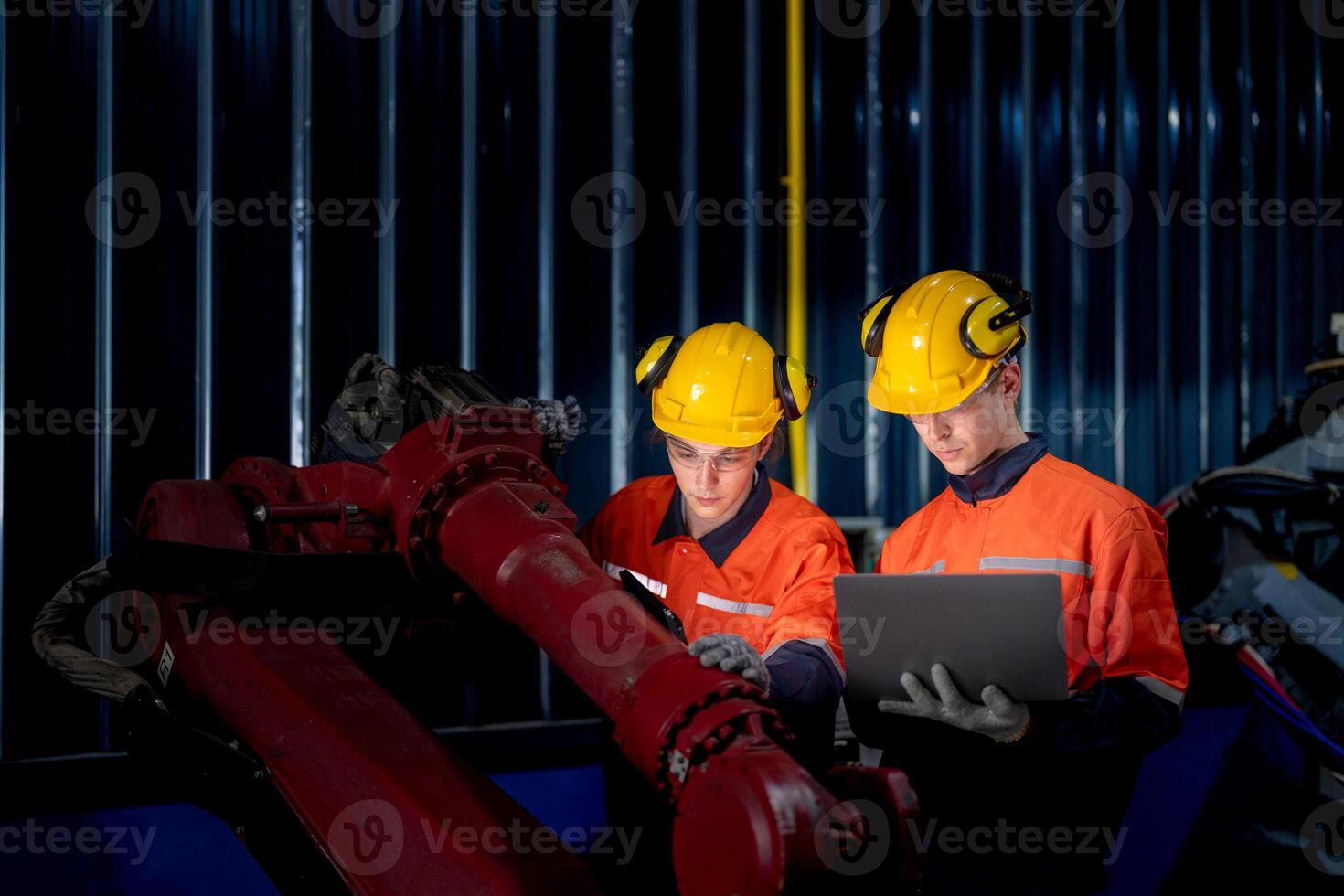 group of male engineer workers maintenance automatic robotic arm machine in a dark room factory. worker checking and repairing automatic robot hand machine. Worker wearing safety glasses and helmet. photo