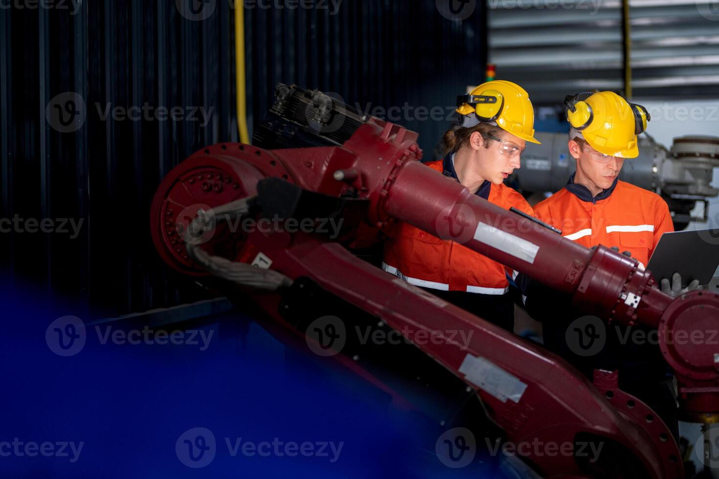group of male engineer workers maintenance automatic robotic arm machine in a dark room factory. worker checking and repairing automatic robot hand machine. Worker wearing safety glasses and helmet. photo