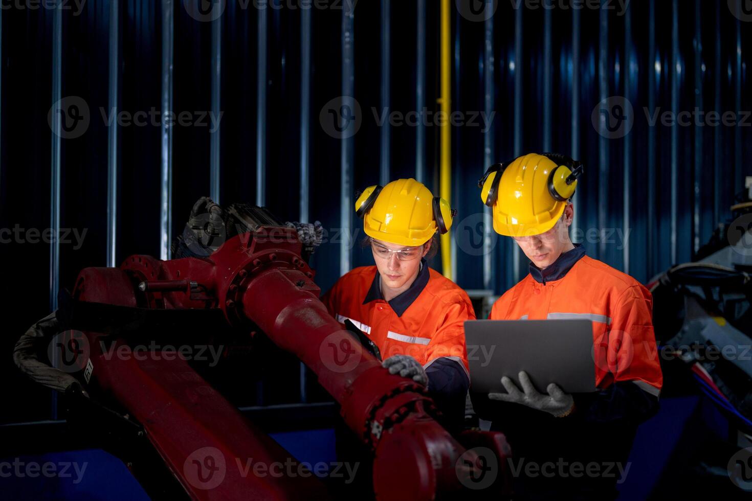 group of male engineer workers maintenance automatic robotic arm machine in a dark room factory. worker checking and repairing automatic robot hand machine. Worker wearing safety glasses and helmet. photo