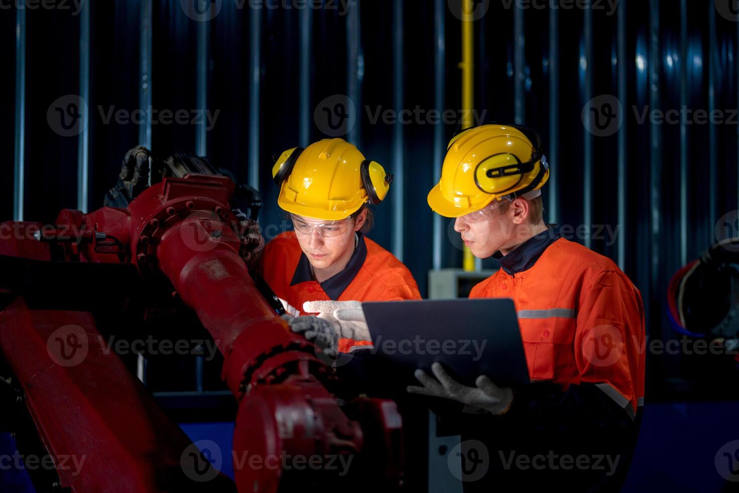 group of male engineer workers maintenance automatic robotic arm machine in a dark room factory. worker checking and repairing automatic robot hand machine. Worker wearing safety glasses and helmet. photo