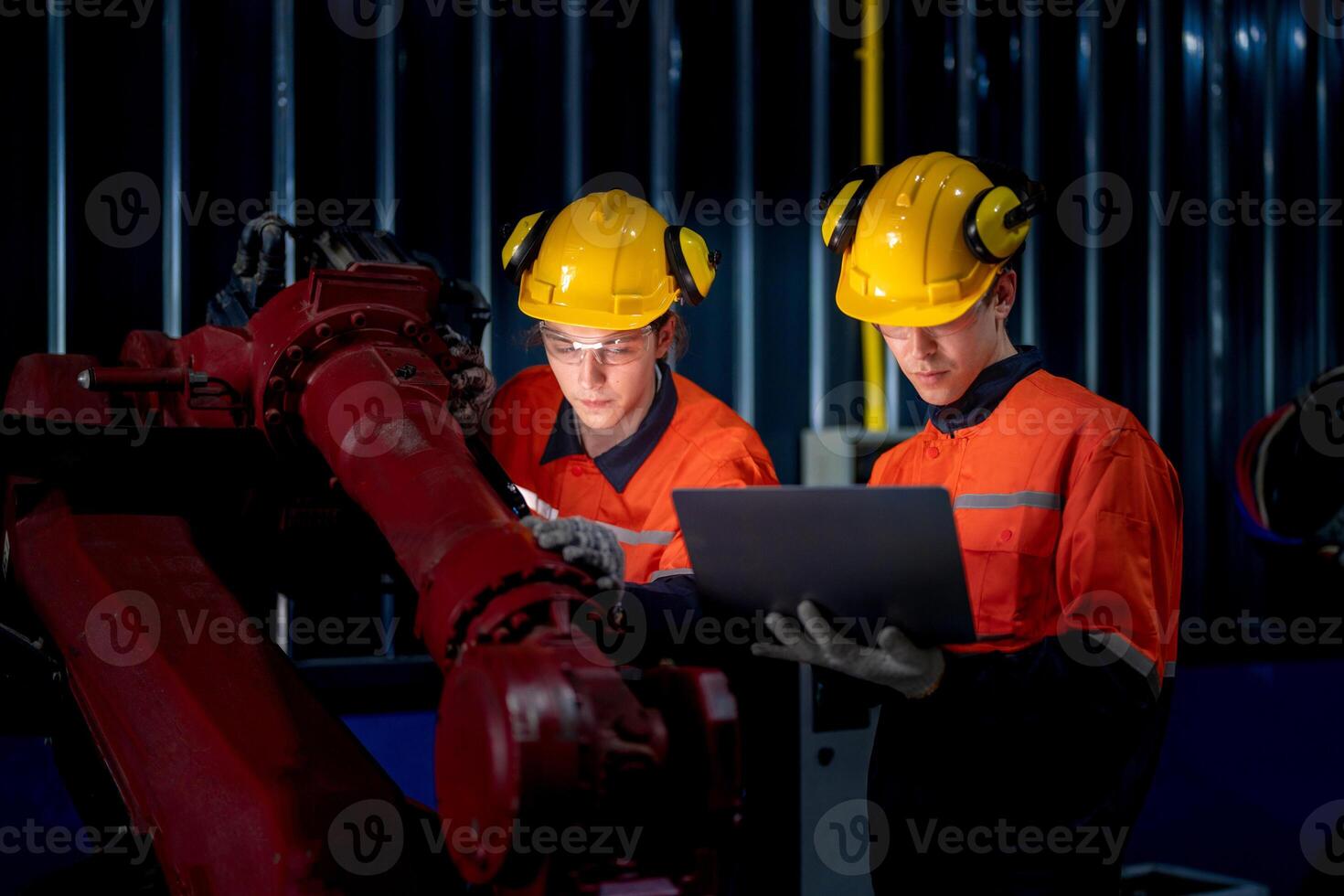 group of male engineer workers maintenance automatic robotic arm machine in a dark room factory. worker checking and repairing automatic robot hand machine. Worker wearing safety glasses and helmet. photo