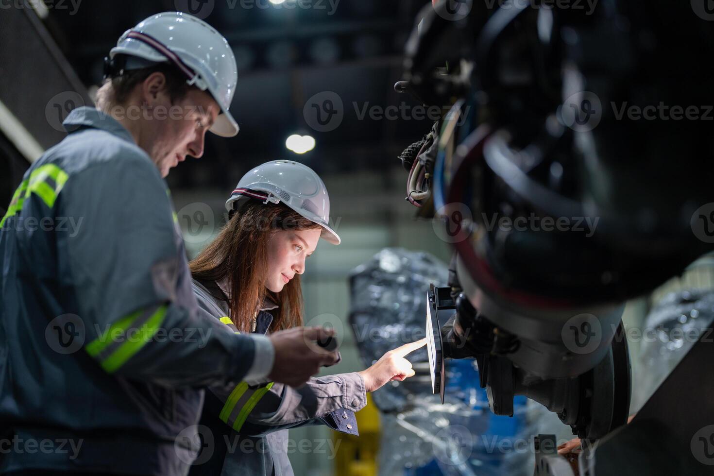 engineers check control heavy machine robot arm. Diverse Team of Industrial Robotics Engineers Gathered Around Machine. Professional Machinery Operators repair electric robot on bright digital panel. photo