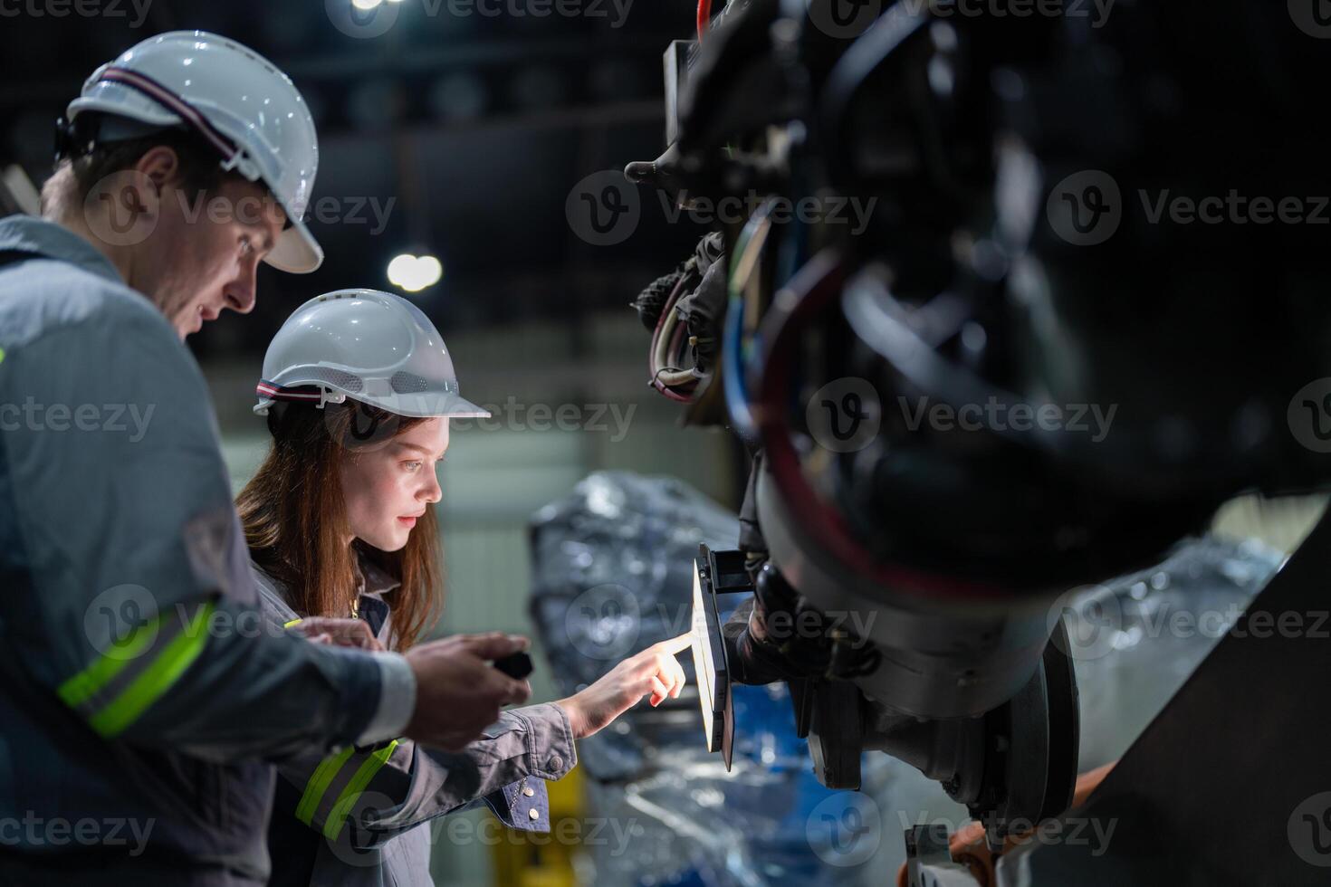 Factory engineer woman inspecting on machine with smart tablet. Worker works at machine robot arm. The welding machine with a remote system in an industrial factory. Artificial intelligence concept. photo