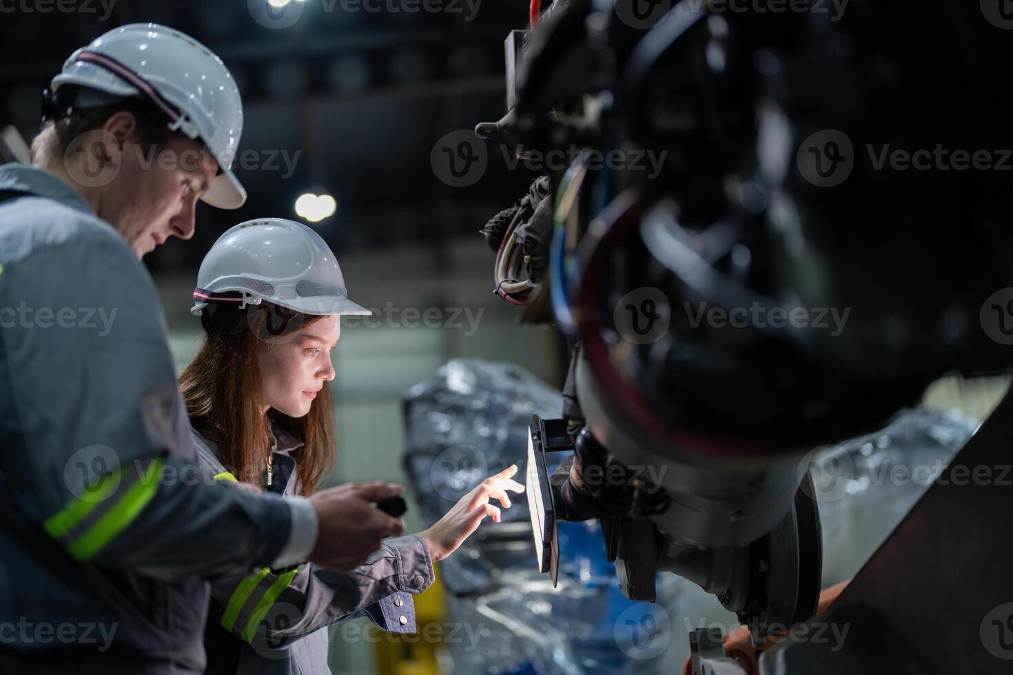 Factory engineer woman inspecting on machine with smart tablet. Worker works at machine robot arm. The welding machine with a remote system in an industrial factory. Artificial intelligence concept. photo