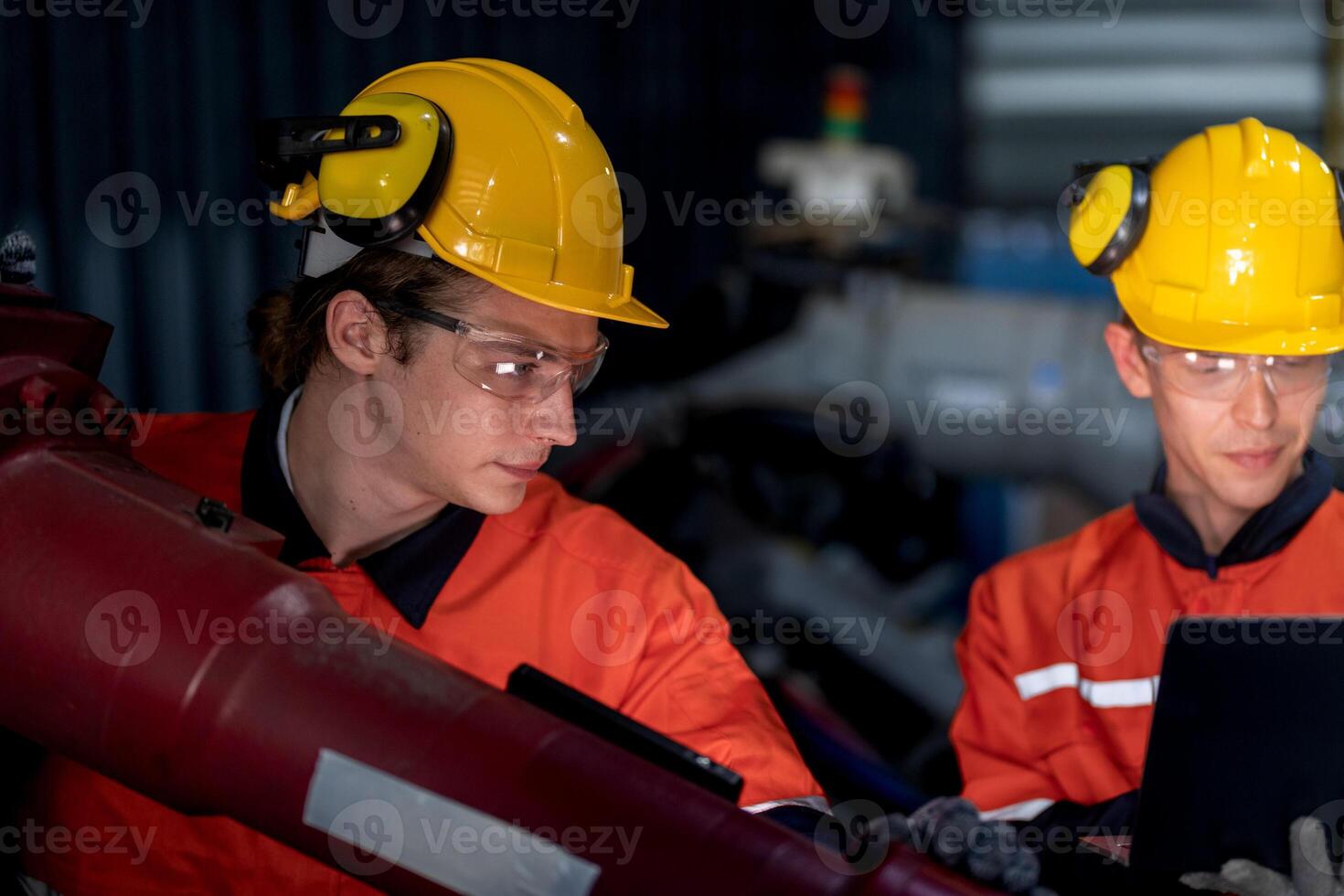 group of male engineer workers maintenance automatic robotic arm machine in a dark room factory. worker checking and repairing automatic robot hand machine. Worker wearing safety glasses and helmet. photo